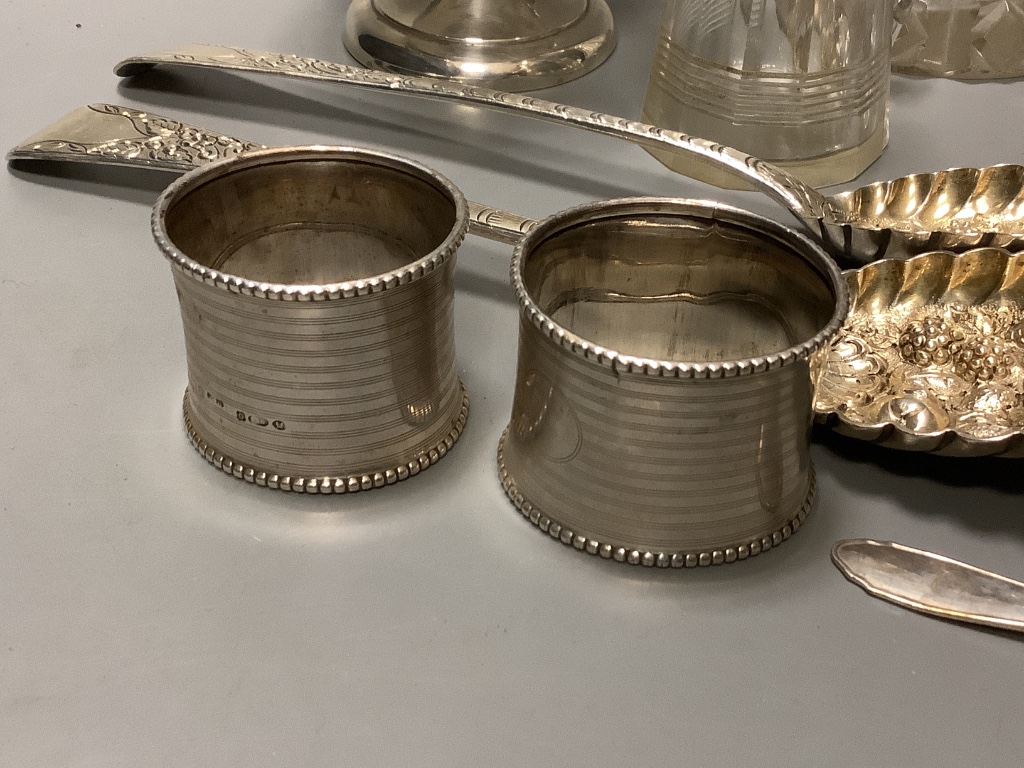 A mixed group of silver including a pair of George III silver Berry spoons, a pair of silver napkin rings, silver nut dish, white metal tea strainer a silver mounted whisky tot jug, 800 spoon, small silver pedestal bowl